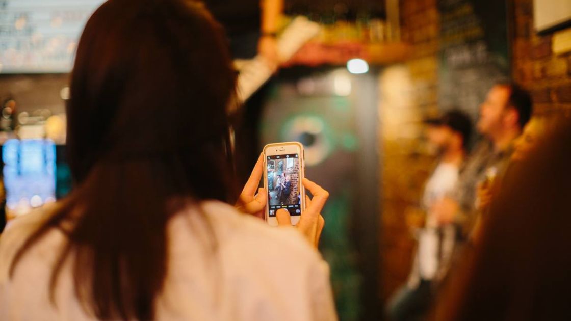 The back of a woman holding an iphone during an event