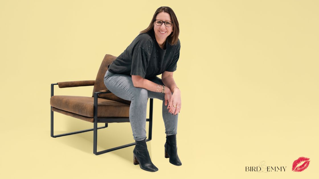 Suz Bird sitting on the arm of a chair in a content studio